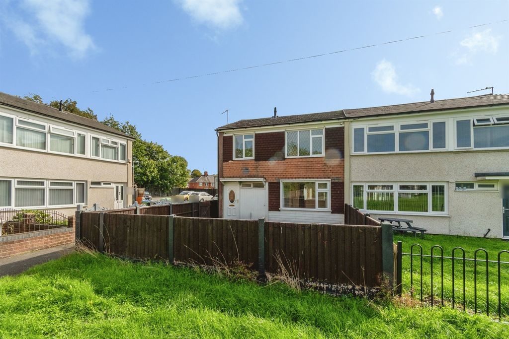 End-of-terrace house with a red tile-hung front, fenced front garden and lawn
